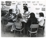 Teacher surrounded by students looking at books by Indiana State University, University Archives